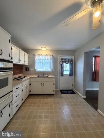 a kitchen with stainless steel appliances a stove a sink and white cabinets