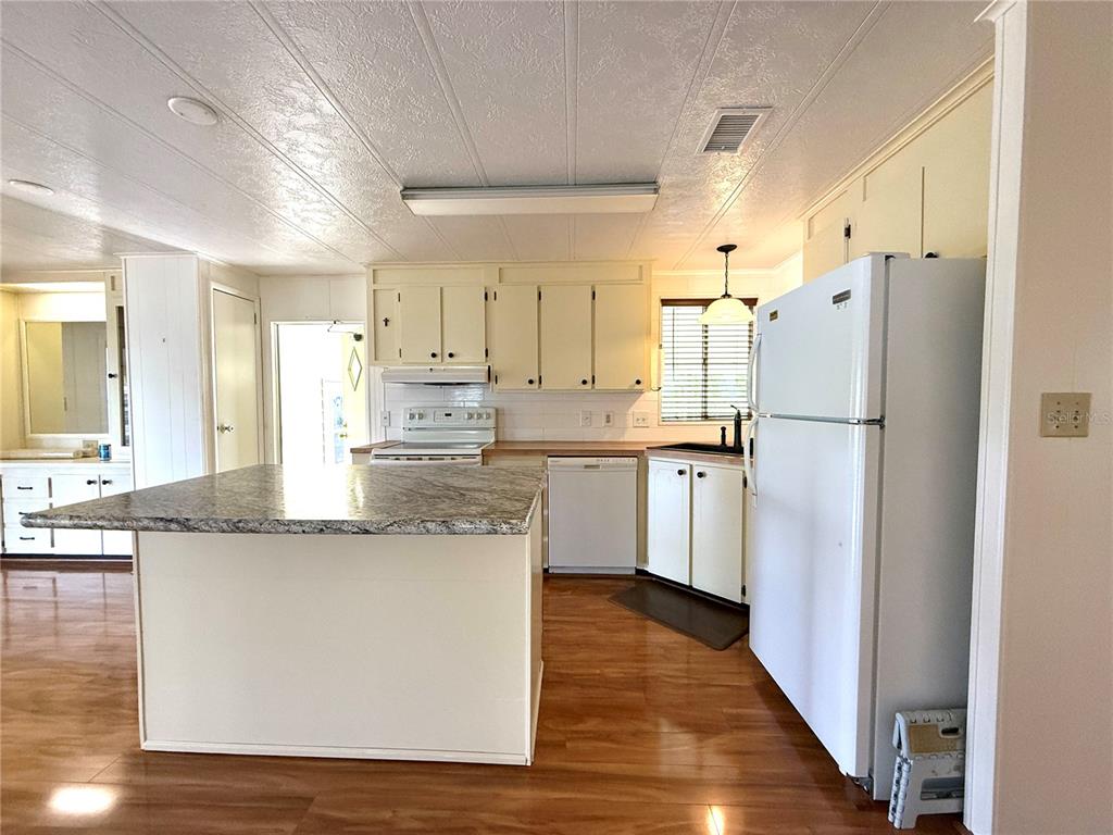 210 North St Thomas Circle Apollo Beach, FL 33572 - Photo 12 of 34 a kitchen with stainless steel appliances granite countertop a refrigerator a sink dishwasher a stove and white countertops with wooden floor