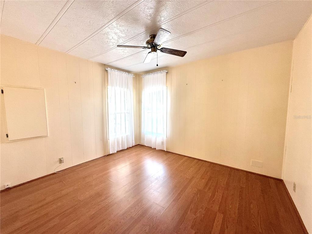 210 North St Thomas Circle Apollo Beach, FL 33572 - Photo 19 of 34 an empty room with wooden floor chandelier fan and windows