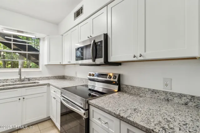 a kitchen with stainless steel appliances granite countertop a sink stove and microwave