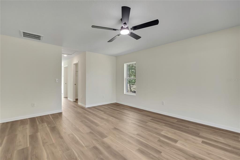 11929 West Cornflower Drive Crystal River, FL 34428 - Photo 20 of 50 a view of an empty room with wooden floor and a ceiling fan
