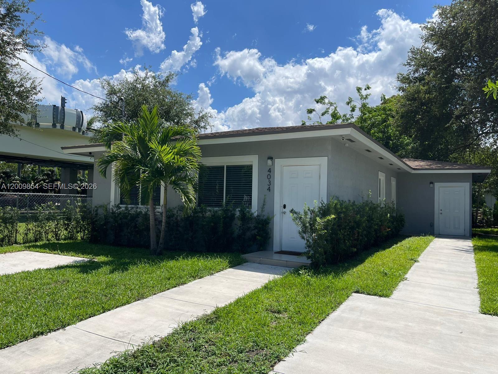 4034 Northwest 23rd Avenue Miami, FL 33142 - Photo 1 of 10 a front view of a house with a yard and potted plants