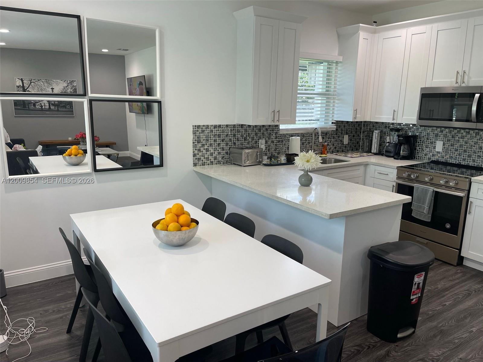 4034 Northwest 23rd Avenue Miami, FL 33142 - Photo 6 of 10 a kitchen with a sink a stove and chairs