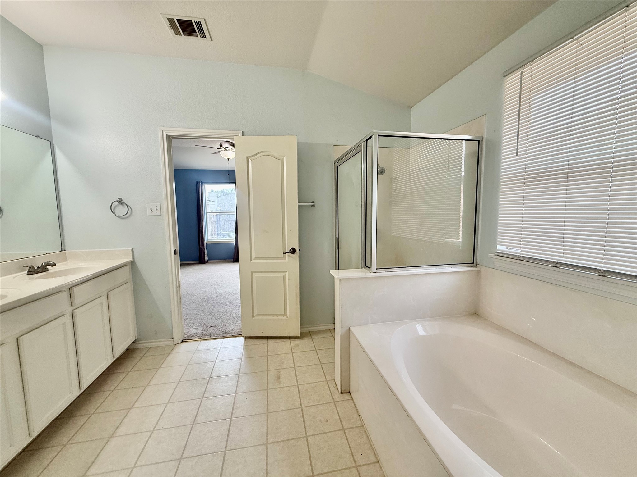 12820 Waynespur Lane Elgin, TX 78621 - Photo 18 of 26 Full bathroom with vanity, a stall shower, a bath, light tile patterned floors, and lofted ceiling