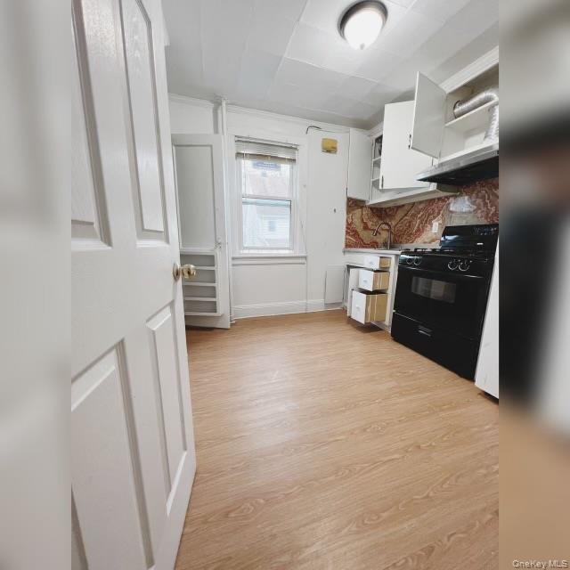 80-41 159th Street Queens, NY 11366 - Photo 2 of 13 Kitchen with open shelves, black gas stove, white cabinets, light wood-style floors, and range hood