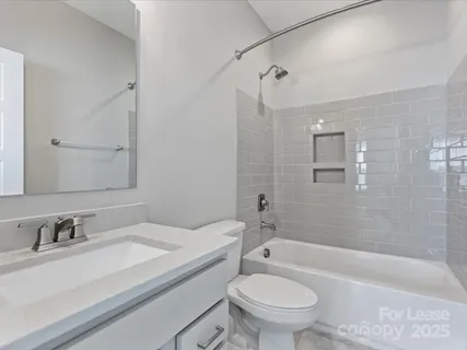 a bathroom with a granite countertop sink a toilet a mirror a bathtub and shower