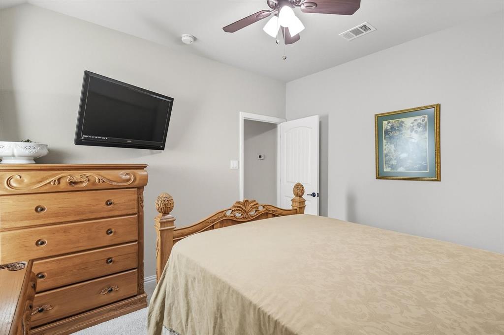 142 High Ridge Court Decatur, TX 76234 - Photo 23 of 40 a bedroom with a bed a flat screen tv and a chandelier