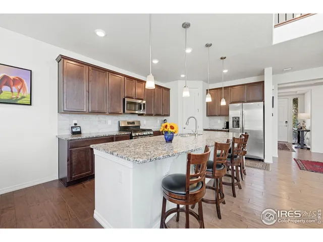 a kitchen with stainless steel appliances kitchen island granite countertop a table chairs sink and cabinets