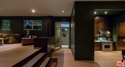 a living room with stainless steel appliances furniture a rug and a view of kitchen