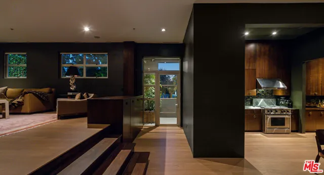 a living room with stainless steel appliances furniture a rug and a view of kitchen