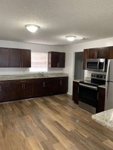 a large kitchen with stainless steel appliances wooden cabinets and a granite counter tops