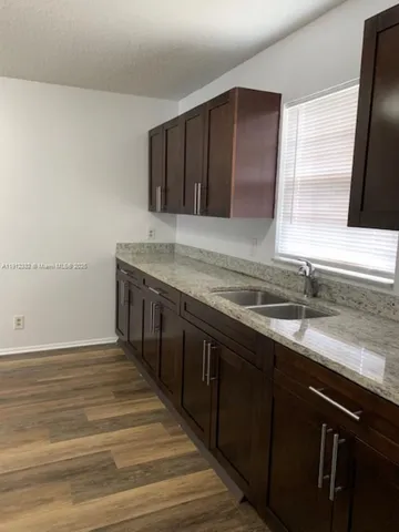 a kitchen with a sink and a wooden floor