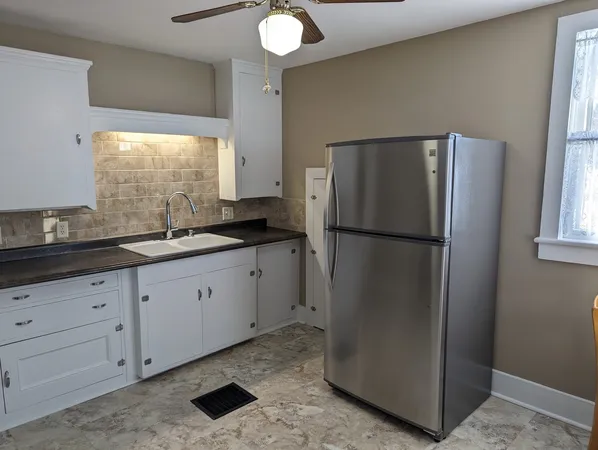a kitchen with granite countertop a stove top oven microwave and refrigerator