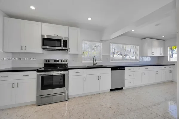 a kitchen with granite countertop white cabinets stainless steel appliances and a sink