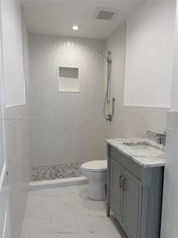 a bathroom with a granite countertop sink a toilet and a mirror