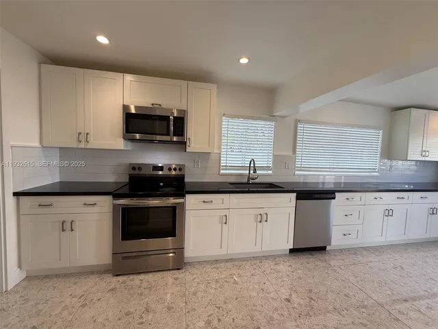 a kitchen with granite countertop a stove a sink and a microwave