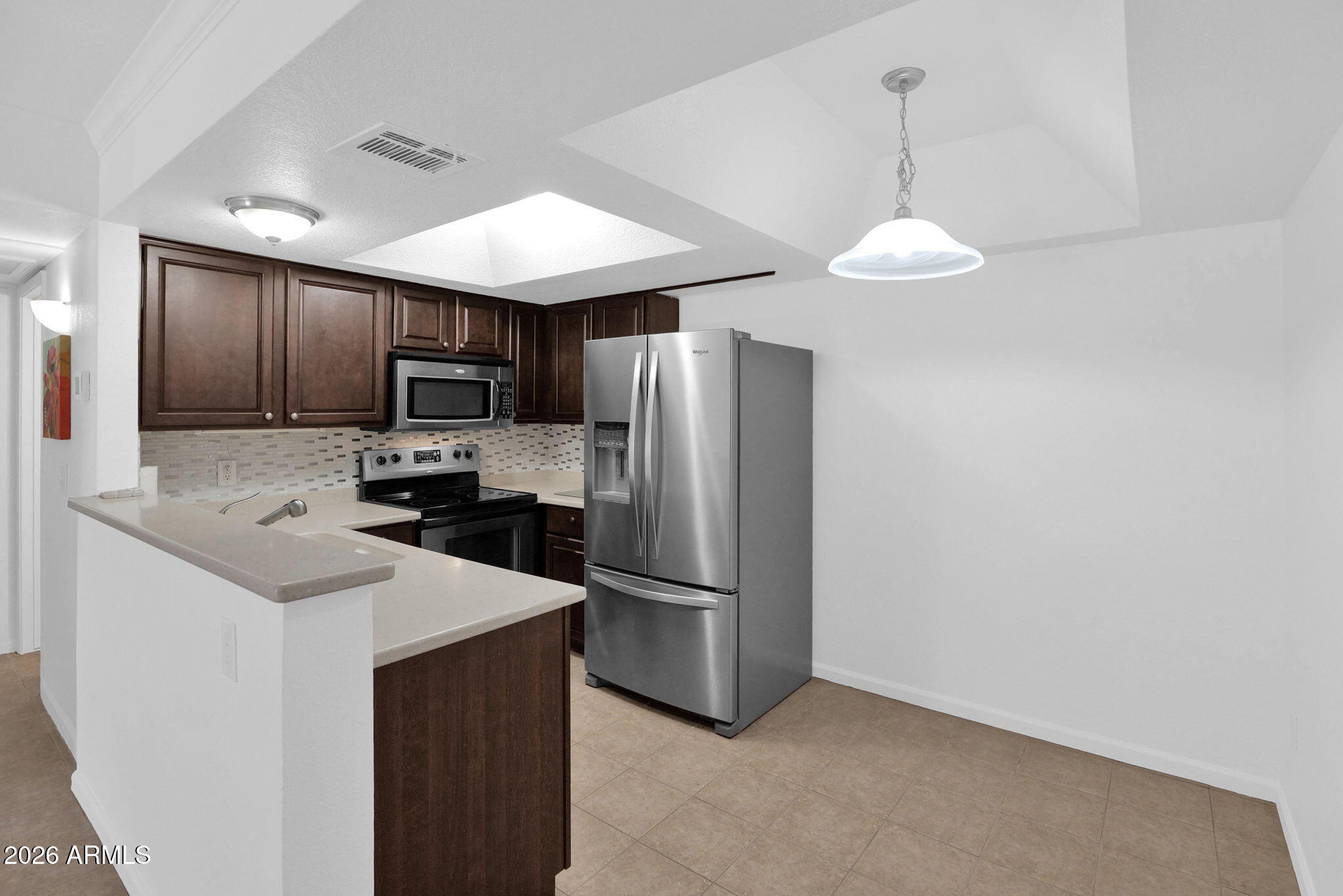 1720 East Thunderbird Road, Unit 1019 Phoenix, AZ 85022 - Photo 11 of 47 a kitchen with kitchen island granite countertop stainless steel appliances cabinets a sink and a refrigerator