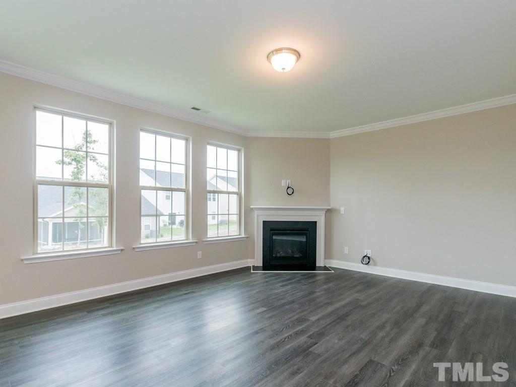 131 Weldon Lane Angier, NC 27501 - Photo 5 of 24 an empty room with wooden floor fireplace and windows