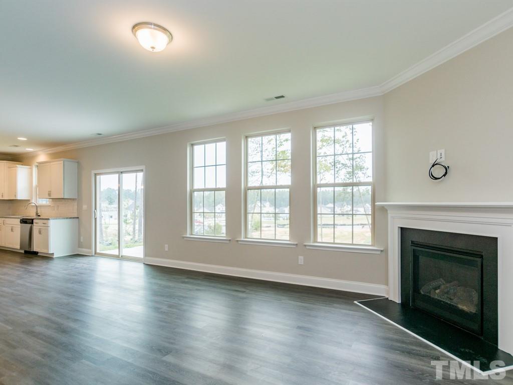 131 Weldon Lane Angier, NC 27501 - Photo 6 of 24 an empty room with wooden floor fireplace and windows