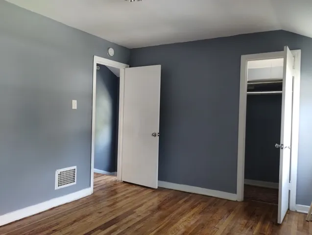 an empty room with wooden floor & closet area
