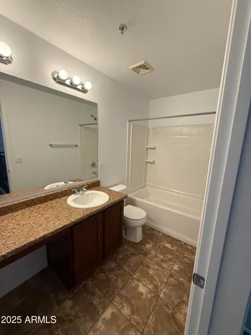 a bathroom with a granite countertop sink a toilet and shower