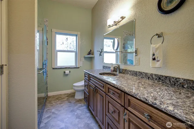 a bathroom with a granite countertop toilet a sink and mirror