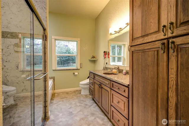 a bathroom with a granite countertop sink toilet and shower