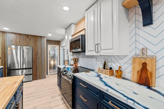 a kitchen with stainless steel appliances granite countertop a refrigerator a stove and a sink with wooden floor