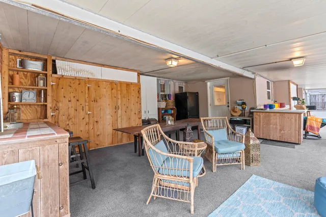 a living room with furniture and a dining table with projector the kitchen