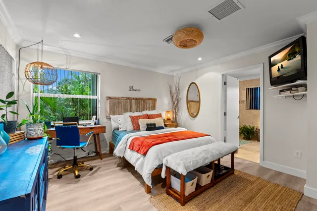 a bedroom with a bed a window and flat screen tv