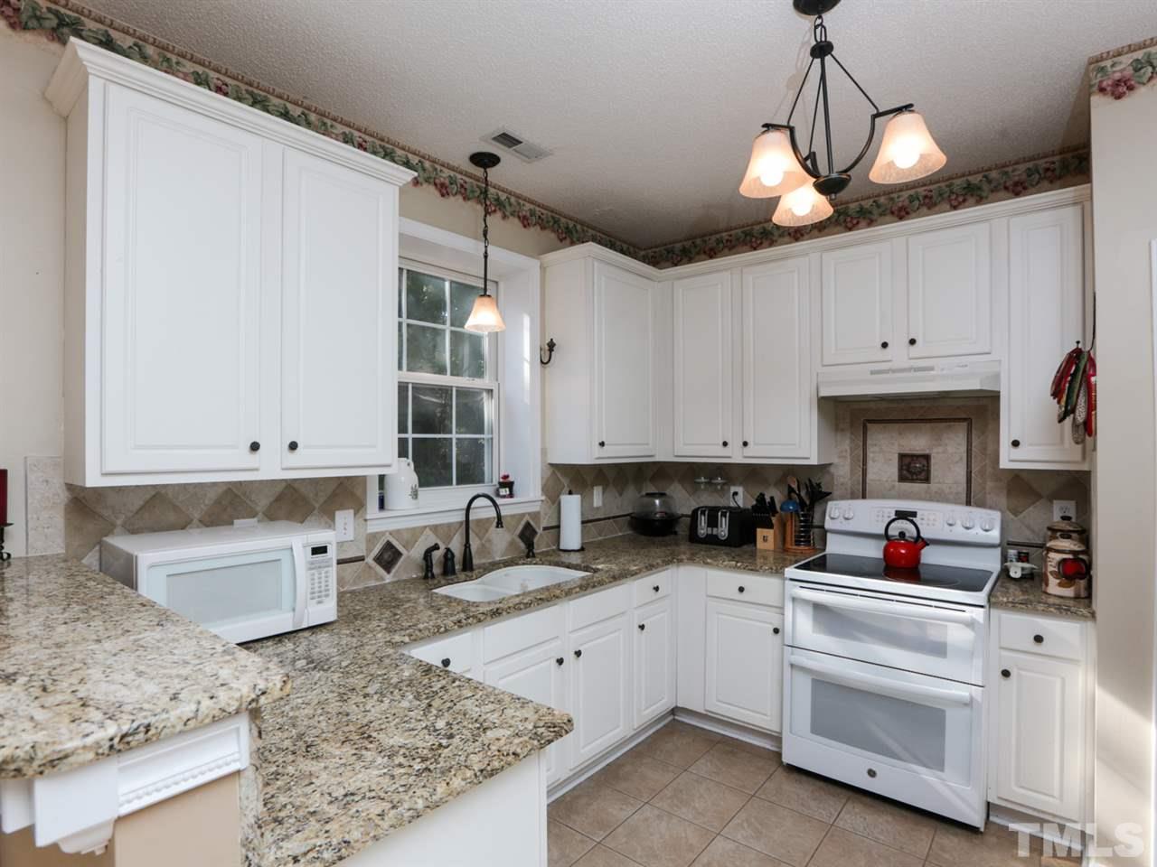 4604 Drewbridge Way Raleigh, NC 27604 - Photo 5 of 24 a kitchen with white cabinets and white appliances
