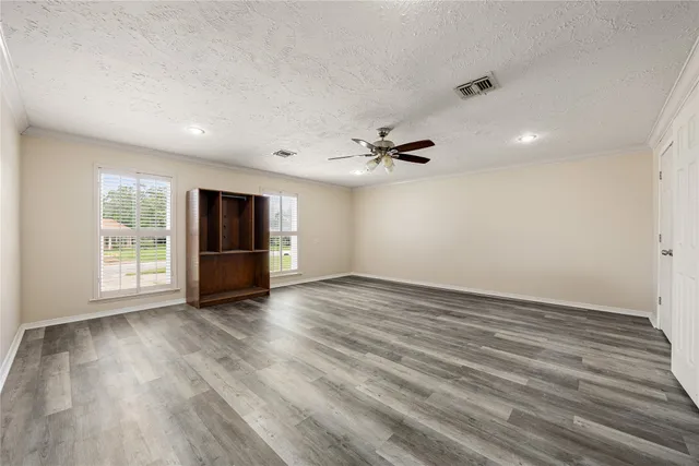 a view of an empty room with a window and wooden floor