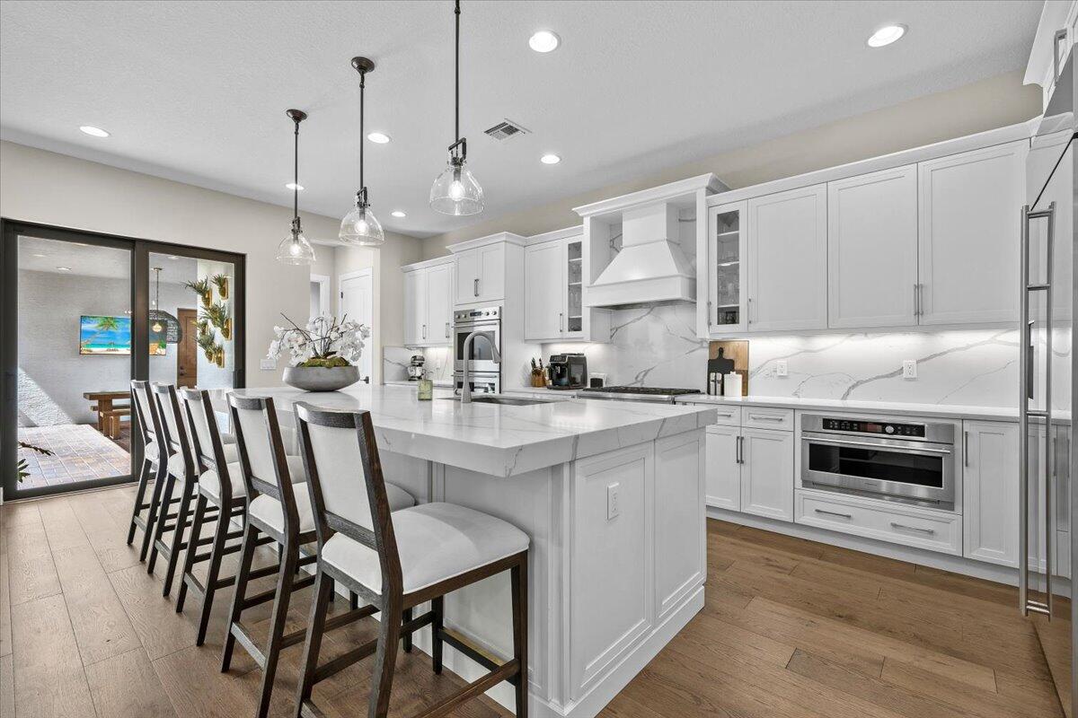 a kitchen with kitchen island granite countertop lots of white cabinets stainless steel appliances and dining table