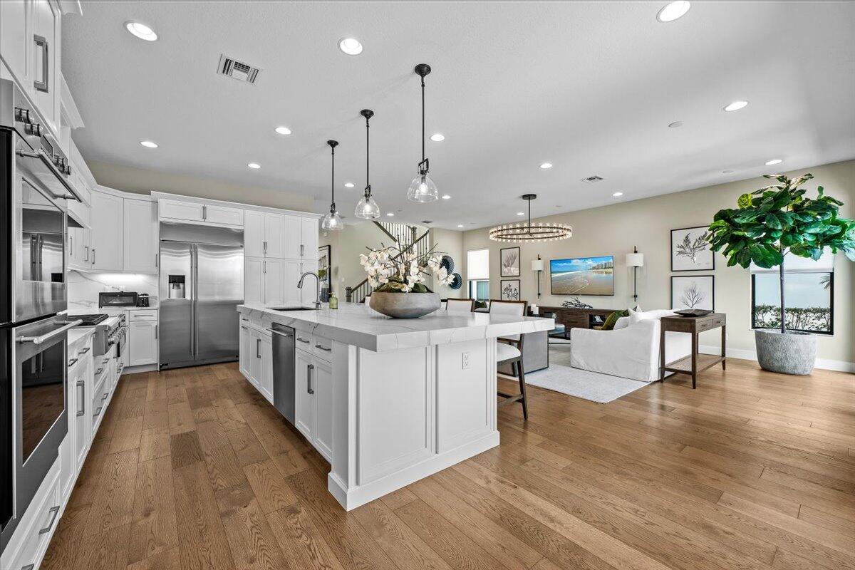 13237 Alton Road Palm Beach Gardens, FL 33418 - Photo 12 of 51 a kitchen with stainless steel appliances kitchen island a refrigerator a stove a sink a dining table and chairs with wooden floor