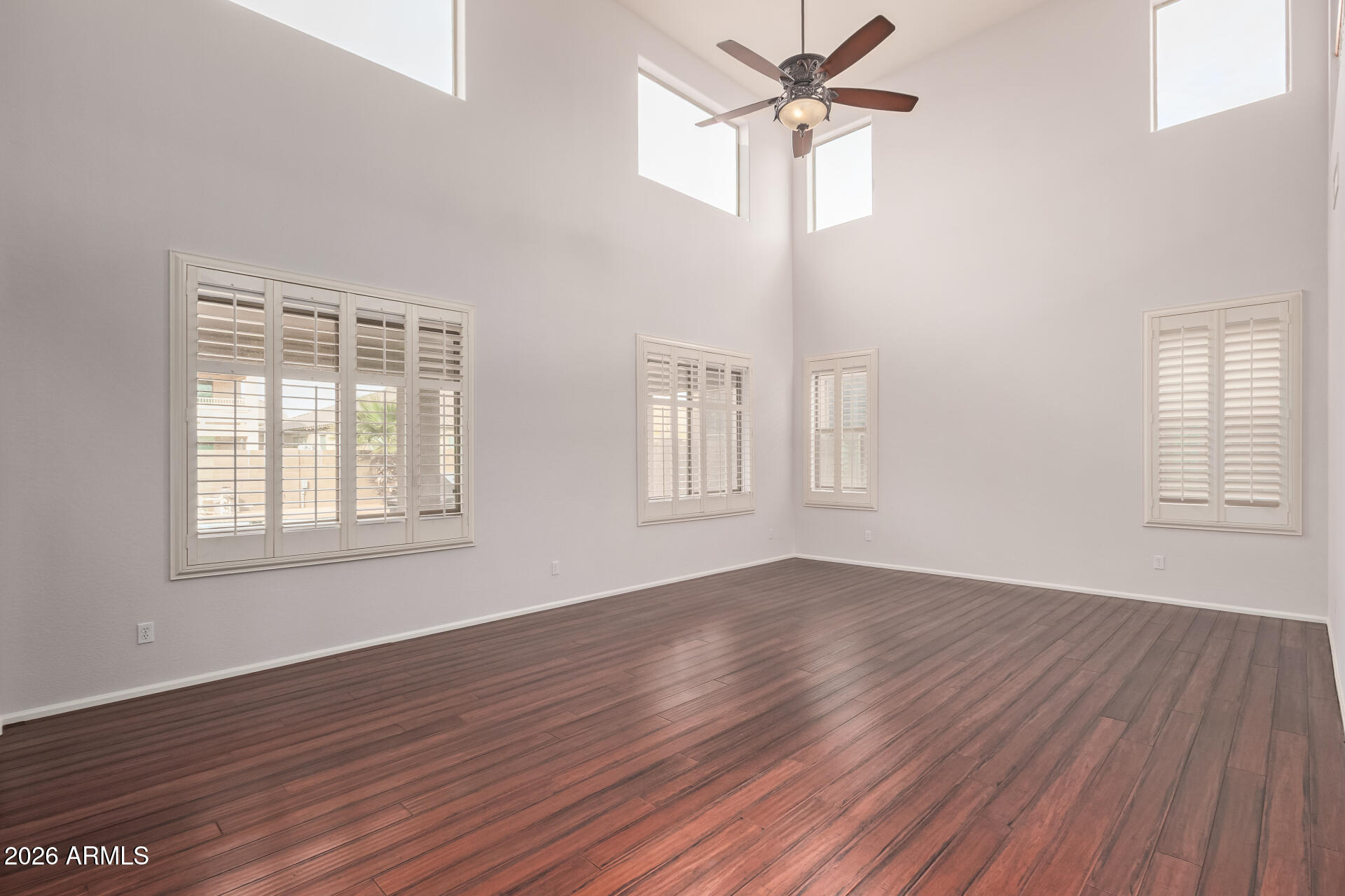41106 West Coltin Way Maricopa, AZ 85138 - Photo 6 of 51 an empty room with wooden floor ceiling fan and windows
