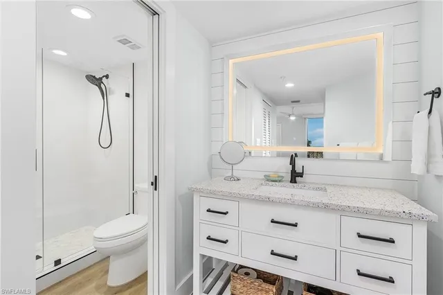 a bathroom with a granite countertop sink a toilet and shower