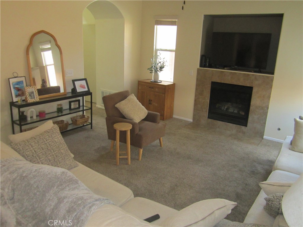 3908 Manquelo Court Perris, CA 92571 - Photo 6 of 36 a living room with furniture a fireplace and a flat screen tv