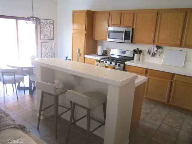 a kitchen with stainless steel appliances granite countertop a stove top oven a sink a dining table and chairs