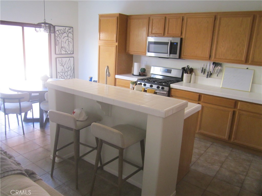 3908 Manquelo Court Perris, CA 92571 - Photo 9 of 36 a kitchen with stainless steel appliances granite countertop a stove top oven a sink a dining table and chairs