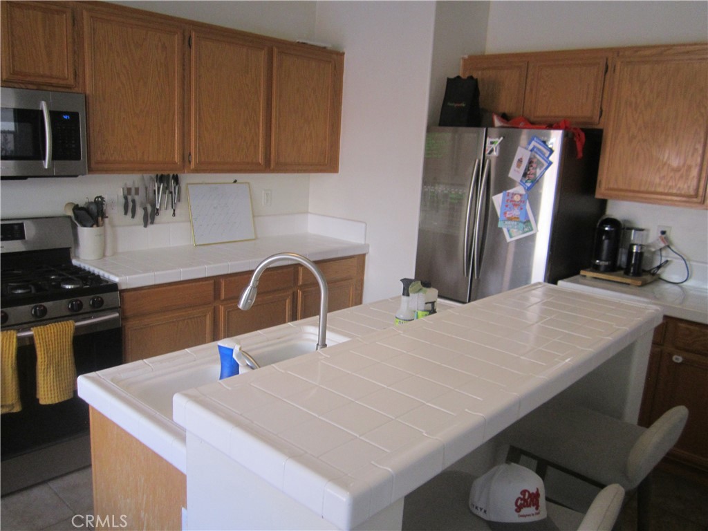 3908 Manquelo Court Perris, CA 92571 - Photo 10 of 36 a kitchen with stainless steel appliances kitchen island a sink a table and chairs