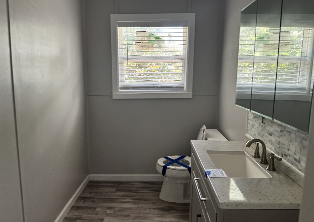 1813 Rhodes Road Austin, TX 78721 - Photo 11 of 14 Modern bath with plank flooring and a sleek vanity featuring a single basin.