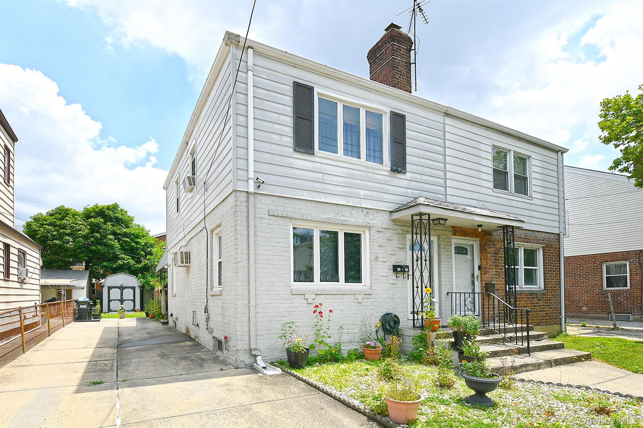 View of front of home with brick siding, a shed, and a chimney