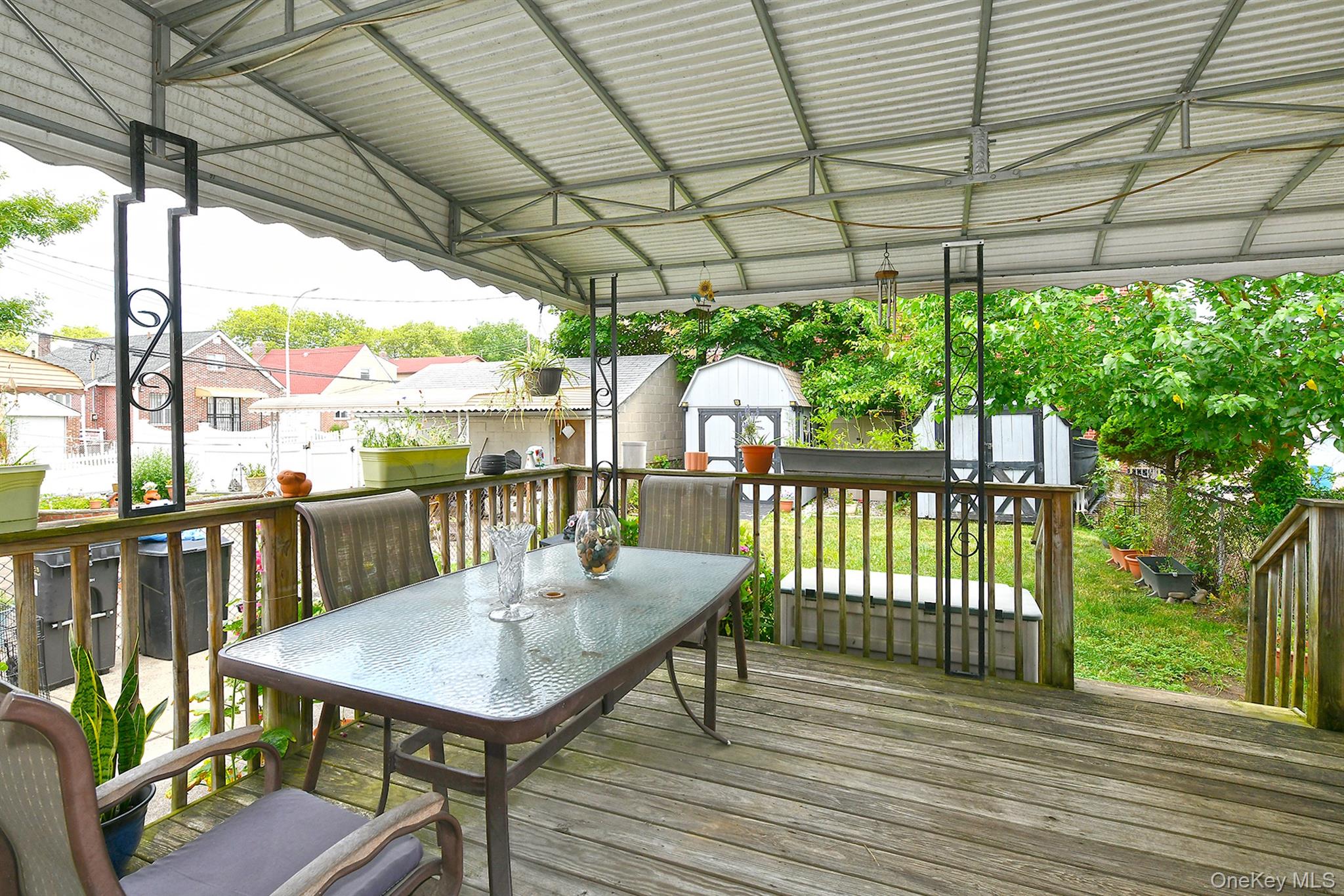 63-05 138th Street Queens, NY 11367 - Photo 18 of 22 Wooden terrace with a storage shed, outdoor dining area, and a residential view
