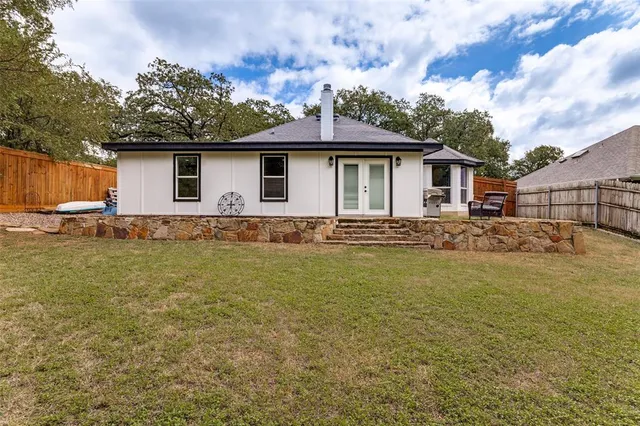 a white house that has a small yard with a large tree