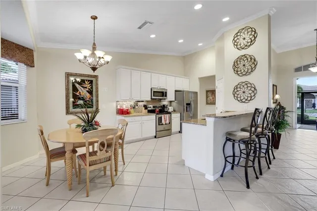 a view of a dining room with furniture a chandelier and kitchen view