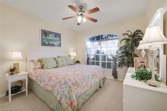 a bedroom with a large bed and a chandelier fan