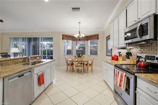 a kitchen with stainless steel appliances granite countertop a stove top oven a sink dishwasher and white cabinets with wooden floor