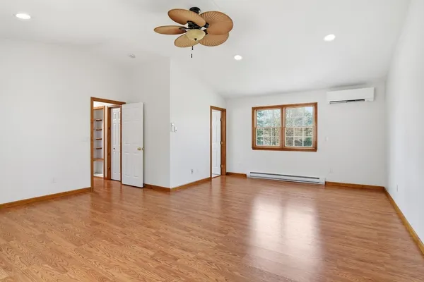 a view of an empty room with a window and wooden floor