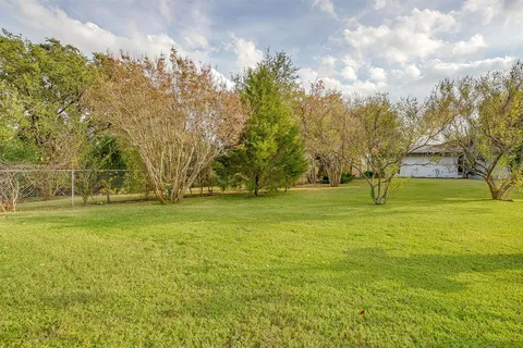 an aerial view of residential house with outdoor space and trees all around