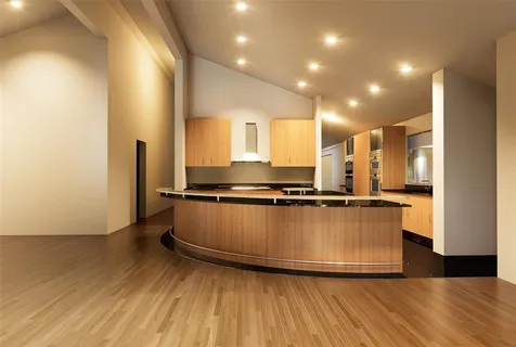 a view of empty room with wooden floor and kitchen